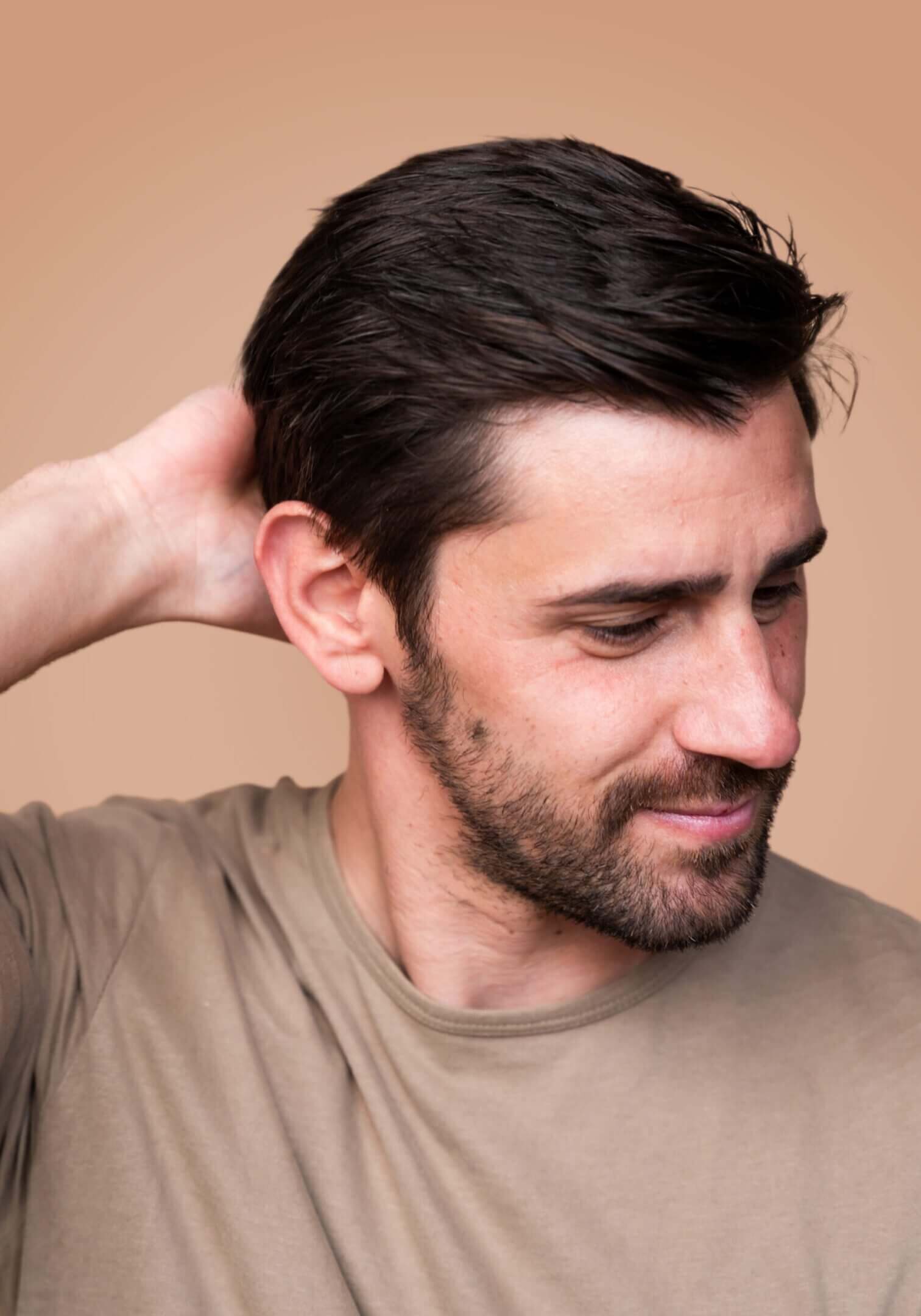 Man in beige shirt, hand behind head.